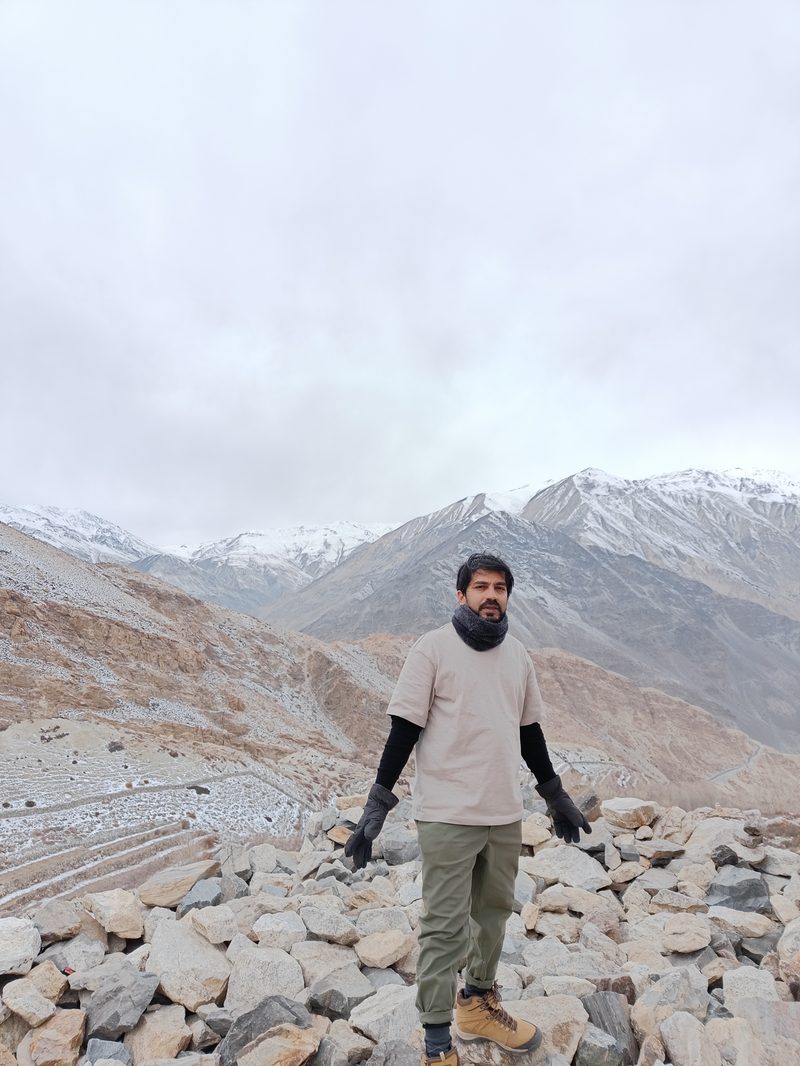Standing on a rocky ridge with snow peaks behind